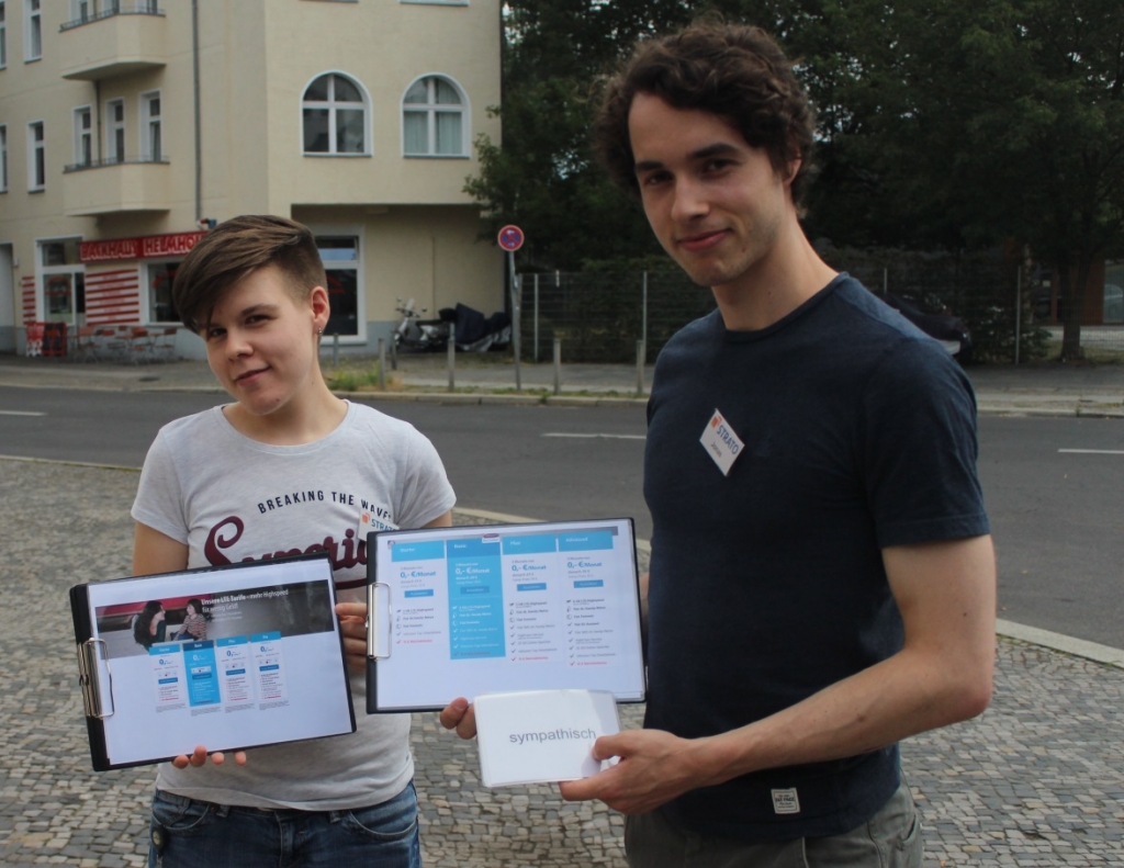 2 STRATO Mitarbeiter zeigen die Screens und Bewertungskarten